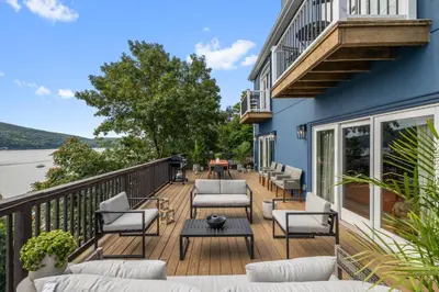 a deck with couches and tables on a house at Lakeview Villa with Private Hot Tub, Firepit & Spacious Decks with Breathtaking Cliff Views in Greenwood Lake