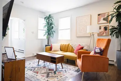 a living room with a yellow couch and a table at Rainforest Retreat 20m to NYC FREE Parking - Sleeps 16 in Bayonne