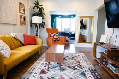 a living room with a yellow couch and orange chairs at Rainforest Retreat 20m to NYC FREE Parking - Sleeps 16 in Bayonne