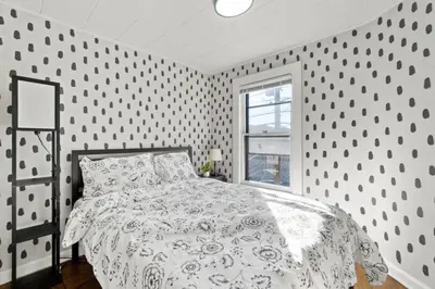 a white bedroom with a bed and a window at Whimsical three in Bayonne