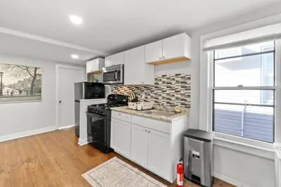 a kitchen with white cabinets and a stove top oven at Whimsical three in Bayonne