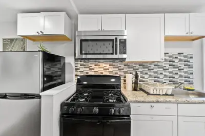 a kitchen with white cabinets and a black stove at Whimsical three in Bayonne