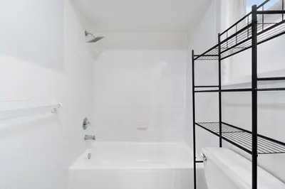 a white bathroom with a white tub and a shelf at UrbanNest XL in Bayonne