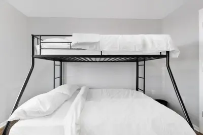 a bedroom with two bunk beds with white sheets at UrbanNest XL in Bayonne