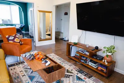 a living room with a flat screen tv on a wall at Rainforest Retreat 20m to NYC Parking Sleeps 25 in Bayonne