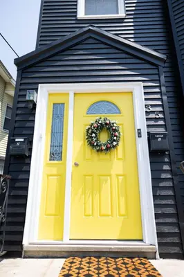 a yellow door on a house with a wreath on it at Rainforest Retreat 20m to NYC Parking Sleeps 25 in Bayonne
