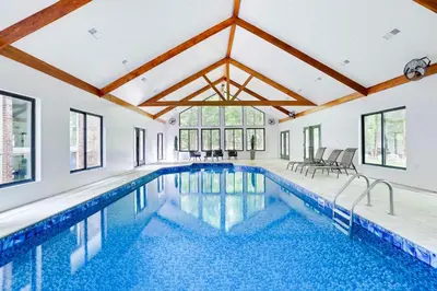 a swimming pool in a house with a large ceiling at Luxury Villa with Year Round Heated Pool, Sauna, Spa & Fire Pit - Newly Redone in East Stroudsburg