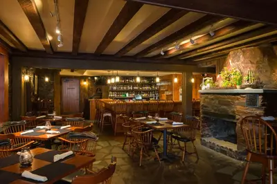 a restaurant with tables and chairs and a fireplace at Pine Barn Inn in Danville