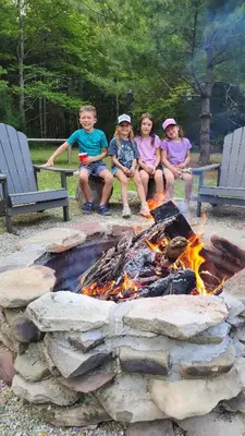 a group of children sitting around a fire pit at Pocono Farmhouse - Fully Renovated 1881 Home in Saylorsburg