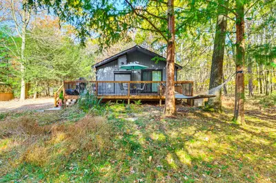 a cabin in the woods with a hammock in front at Peaceful Pocono Gem! Cabin 6 Mi to Dtwn Jim Thorpe in Jim Thorpe
