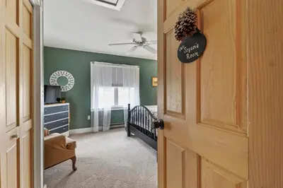 a room with a crib and a bedroom with green walls at Paper Mill Pines Bed and Breakfast in Shickshinny