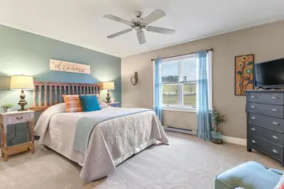 a bedroom with a bed with a ceiling fan and a window at Paper Mill Pines Bed and Breakfast in Shickshinny