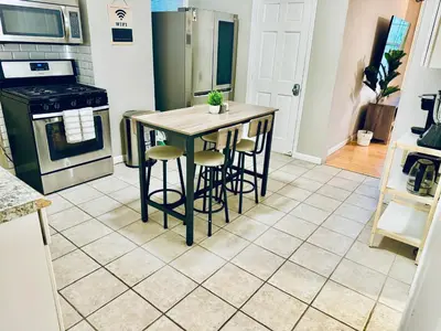 a kitchen with a table and stools in a room at Bright, Stylish & Cozy 2Bed Unit w/Backyard & Grill Close to NYC! in Haledon
