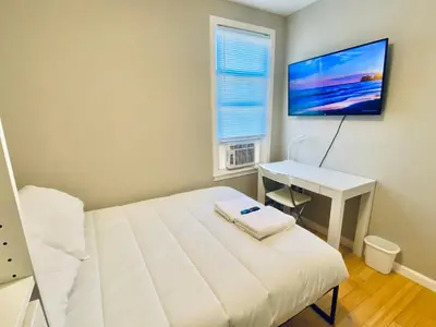 a bedroom with a bed and a desk and a television at Bright, Stylish & Cozy 2Bed Unit w/Backyard & Grill Close to NYC! in Haledon