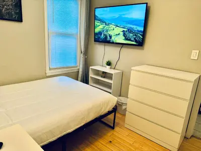 a bedroom with a bed and a flat screen tv at Bright, Stylish & Cozy 2Bed Unit w/Backyard & Grill Close to NYC! in Haledon