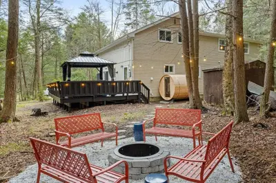 a fire pit with three red benches and a house at Creekside Recess Hottub Sauna Firepit Gameroom