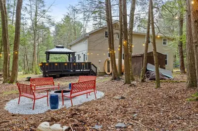 a yard with two red chairs and a gazebo at Creekside Recess Hottub Sauna Firepit Gameroom