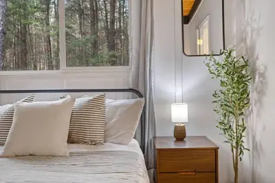 a bedroom with a bed with a window and a lamp at Creekside Recess Hottub Sauna Firepit Gameroom