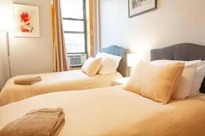 two beds in a room with a window at 2 Bedroom Apt with 3 Beds - Friends & Family in New York