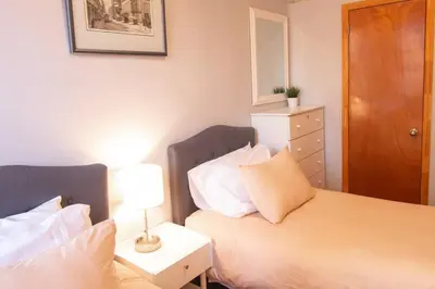 a bedroom with two beds and a table with a lamp at 2 Bedroom Apt with 3 Beds - Friends & Family in New York