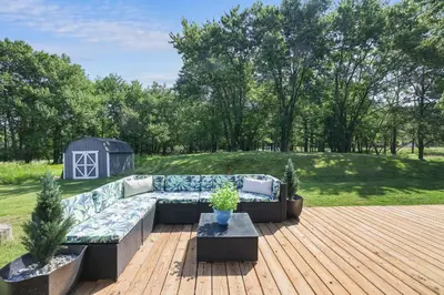 a patio with a couch on a wooden deck at POCONOS BRAND NEW LAKEFRONT Oasis 1 ACRE, HOTTUB GAMEROOM FIREPITS TALK ABOUT PRIVACY in Albrightsville