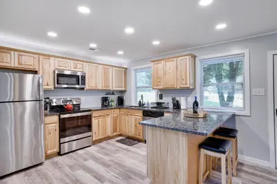 a kitchen with wooden cabinets and stainless steel appliances at POCONOS BRAND NEW LAKEFRONT Oasis 1 ACRE, HOTTUB GAMEROOM FIREPITS TALK ABOUT PRIVACY in Albrightsville