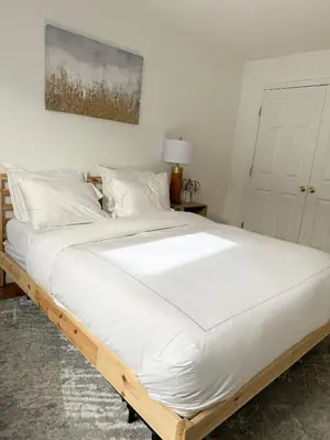 a bedroom with a large bed with white sheets at Stylish Evergreen Apartment By Newark Airport in Newark