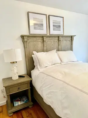 a bed with a wooden headboard and a table with a lamp at Stylish Evergreen Apartment By Newark Airport in Newark