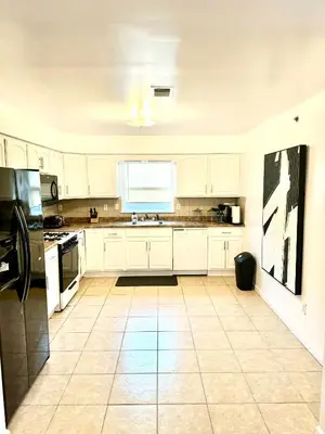 a kitchen with white cabinets and a tile floor at Stylish Evergreen Apartment By Newark Airport in Newark