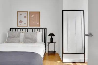 a white bedroom with a bed and a mirror at Little Italy 1br w wd nr SoHo NYC-756 in New York