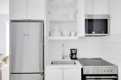 a white kitchen with a refrigerator and a sink at Little Italy 1br w wd nr SoHo NYC-756 in New York