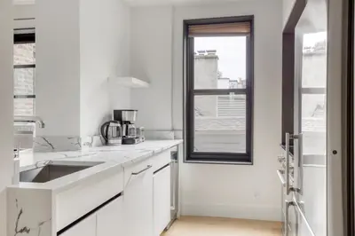 a white kitchen with a sink and a window at BK Heights 2BR w WD Elevator nr Promenade NYC-910 in Brooklyn