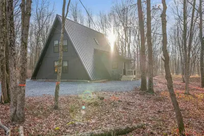 a barn with the sun shining through the trees at Modern A-frame in woods with Sauna, HotTub, Privacy in Albrightsville