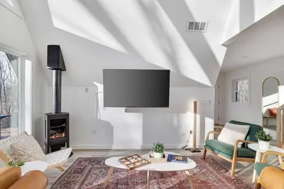 a living room with a fireplace and a flat screen tv at Modern A-frame in woods with Sauna, HotTub, Privacy in Albrightsville