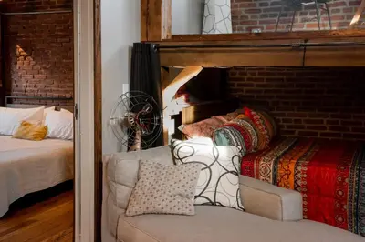 a living room with a couch and a bed and a brick wall at Sweet Lancaster Apt. A in Lancaster