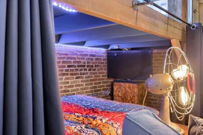 a room with a bed and a tv and a brick wall at Sweet Lancaster Suite in Lancaster