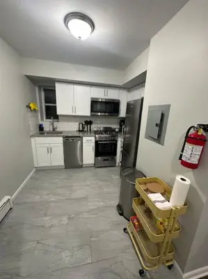 a kitchen with white cabinets and a tile floor at Cozy 2 BR suite, 10 min to NYC &Times Sq in West New York