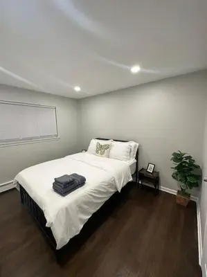 a bedroom with a large bed with white sheets at Cozy 2 BR suite, 10 min to NYC &Times Sq in West New York