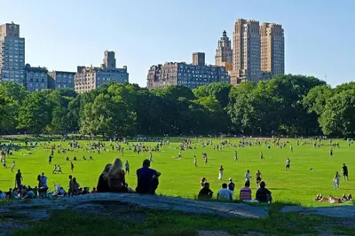 a group of people sitting in a field in a park at 2BR Apt Walk to Restaurants & Time Square in New York