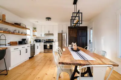 a kitchen with a wooden table and white cabinets at Very Cozy, 2 Bedroom Farmhouse Apartment 2nd FL in Lancaster