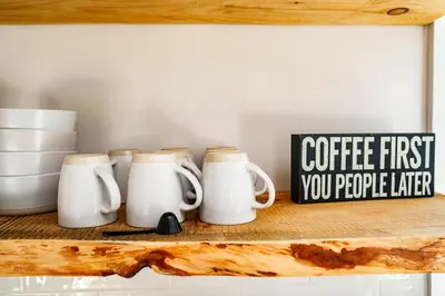a shelf with three coffee cups and a sign on it at Very Cozy, 2 Bedroom Farmhouse Apartment 2nd FL in Lancaster