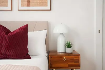 a bed with a red pillow and a table with a lamp at 153-5A Charming 2BR LES W D in New York