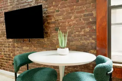 a white table and two green chairs in front of a brick wall at 153-5A Charming 2BR LES W D in New York