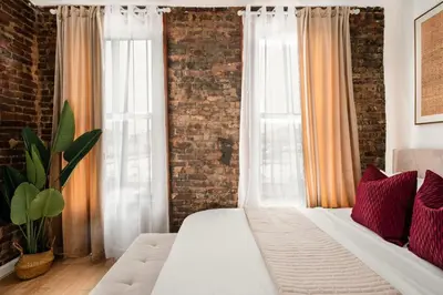 a bedroom with a white bed and a brick wall at 153-5A Charming 2BR LES W D in New York