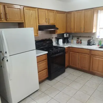 a kitchen with wooden cabinets and a white refrigerator at Cosy Bedroom 12mins to Airport Prudential NJIT UMDJ Penn Station in Newark