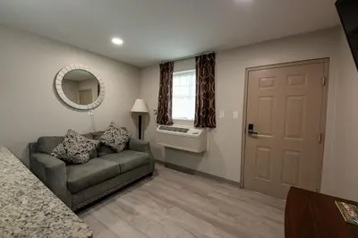 a living room with a couch and a mirror at Lock Haven Grandview Hotel in Mill Hall