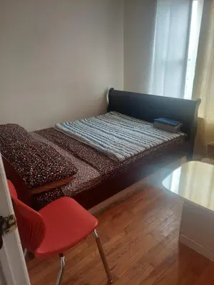 a small bed with a red chair in a room at Crystal Room 1 Guest House near 12mins to EWR airport / Prudential / NJIT / Penn station in Newark
