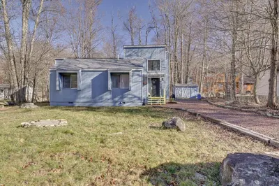 a blue house in the middle of a yard at Fire Pit, Pool and Beach Access Tobyhanna Home! in Tobyhanna