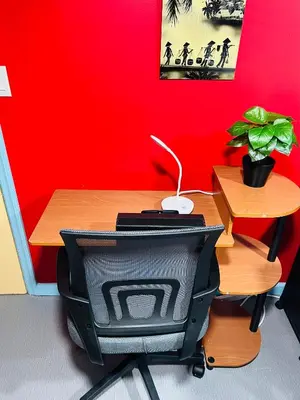 a desk with a computer monitor sitting next to a red wall at Single Room with Bathroom in Irvington