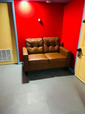 a brown couch in a room with a red wall at Single Room with Bathroom in Irvington